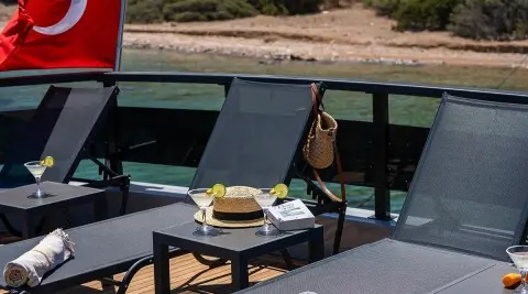 Calm Down yacht sunlounge with seating area and table overlooking water