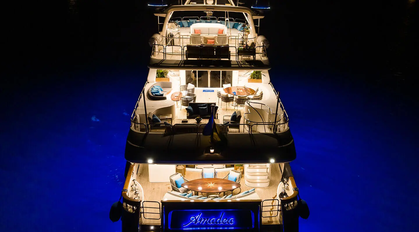 Amadea luxury yacht at night, illuminated decks and stacked hulls in blue water
