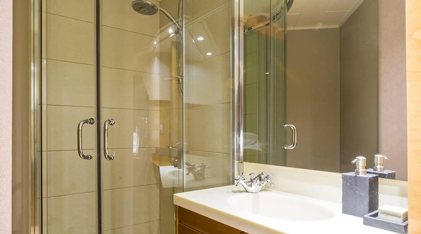 Shower enclosure with glass doors and bathroom sink with faucet visible