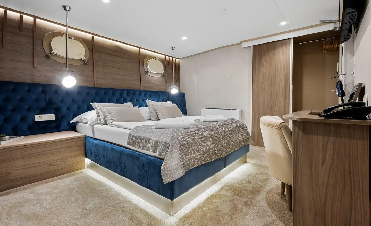 Bella yacht bedroom with king bed, beige seating, and built-in cabinetry