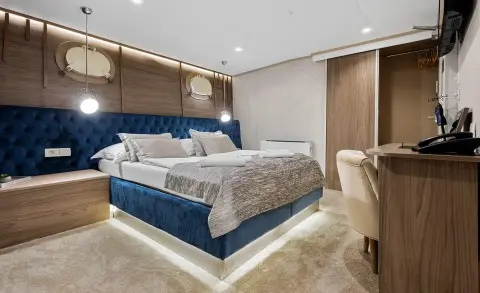 Bella yacht bedroom with king bed, beige seating, and built-in cabinetry