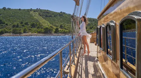 Libra luxury gulet at sunset, passengers on deck railing aboard yacht