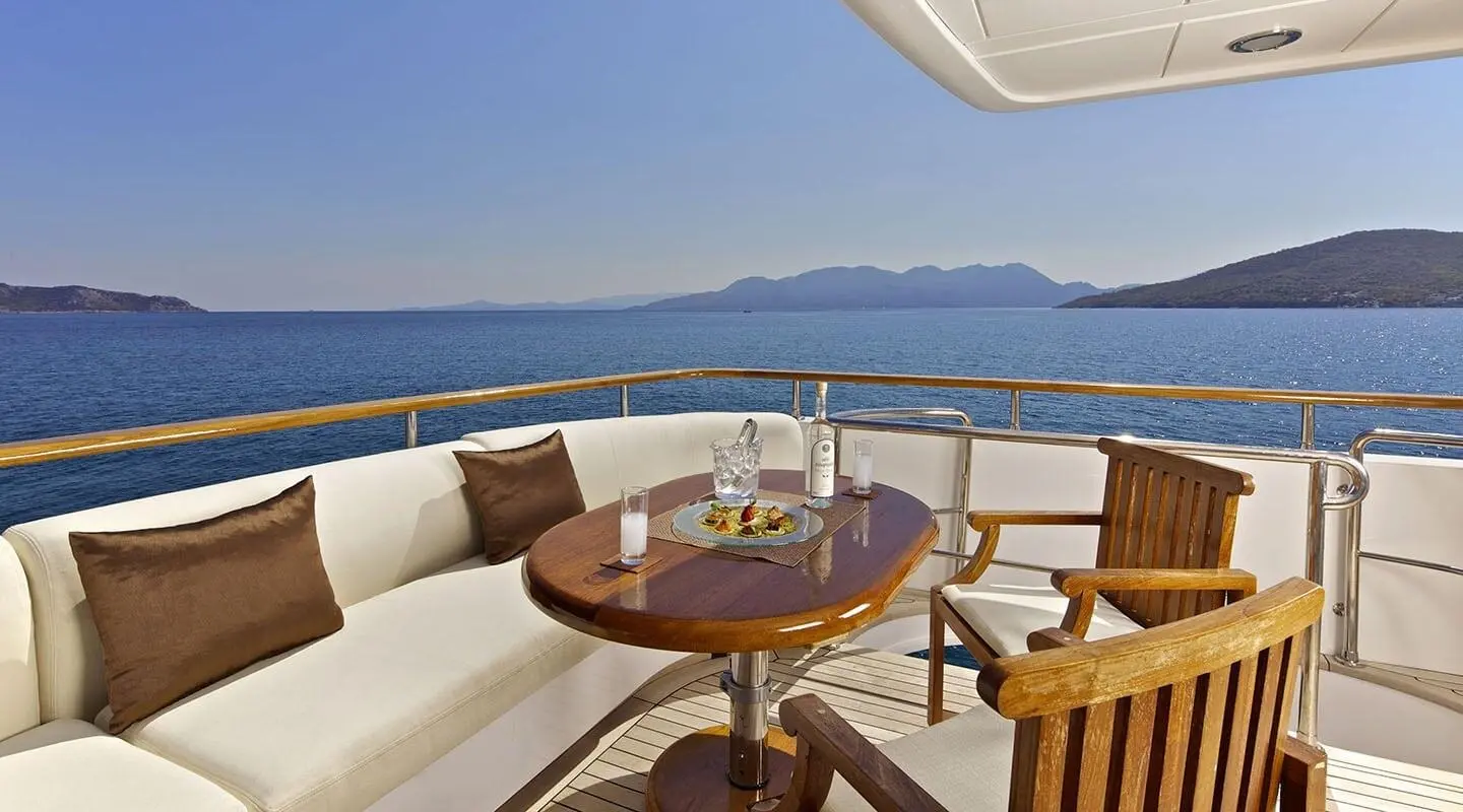 Yacht O'Rion deck seating area facing calm sea at sunset on luxury deck