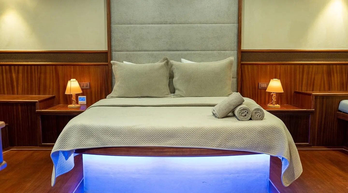 Nevra Queen yacht cabin with bed, beige headboard, window and blue lighting