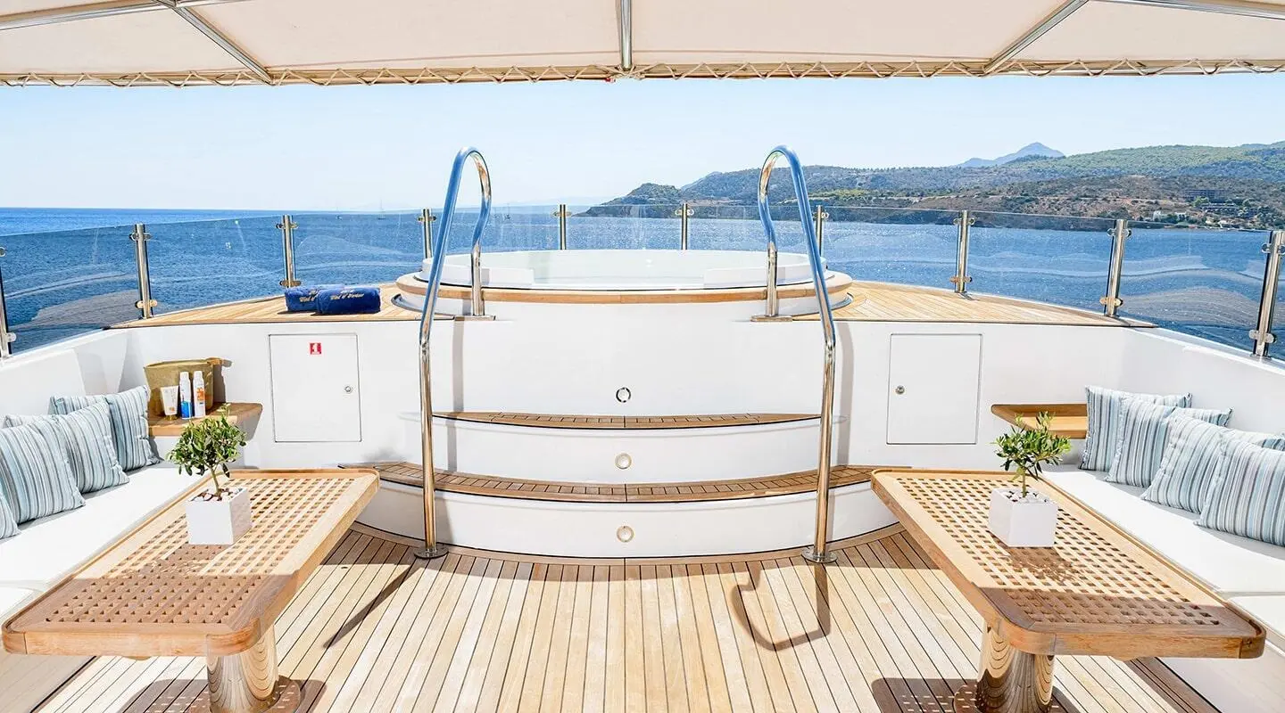 View from yacht Wind Of Fortune deck toward blue sea, beige railing, and distant coastline