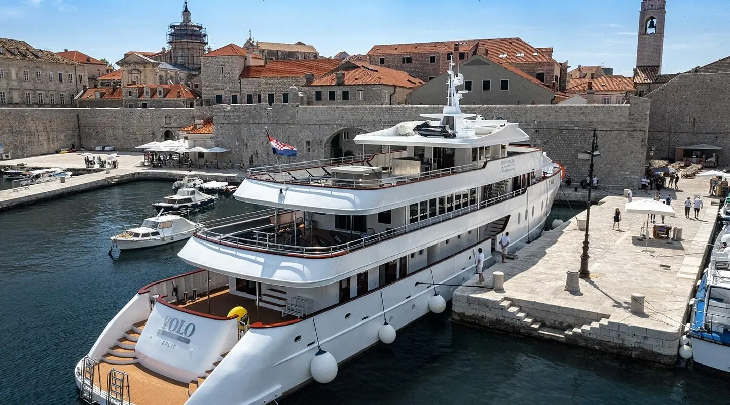 Yolo motor yacht docked in Dubrovnik harbor with red-roofed buildings in background