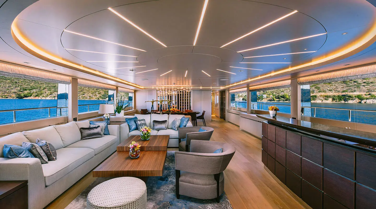 Interior of Xana yacht lounge with seating, tables, and large windows