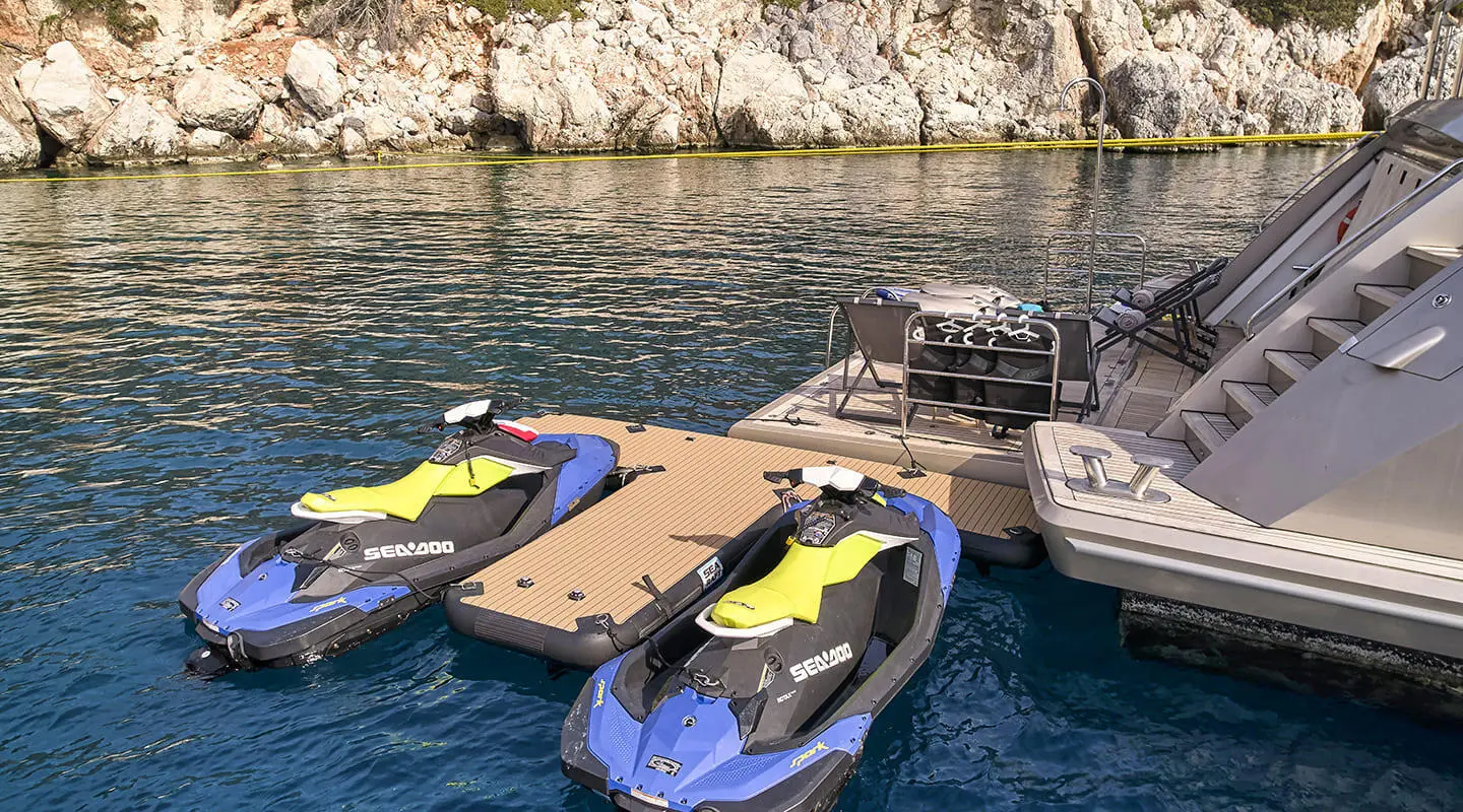 La Pellegrina 1 yacht docked near rocky shoreline with jet skis nearby