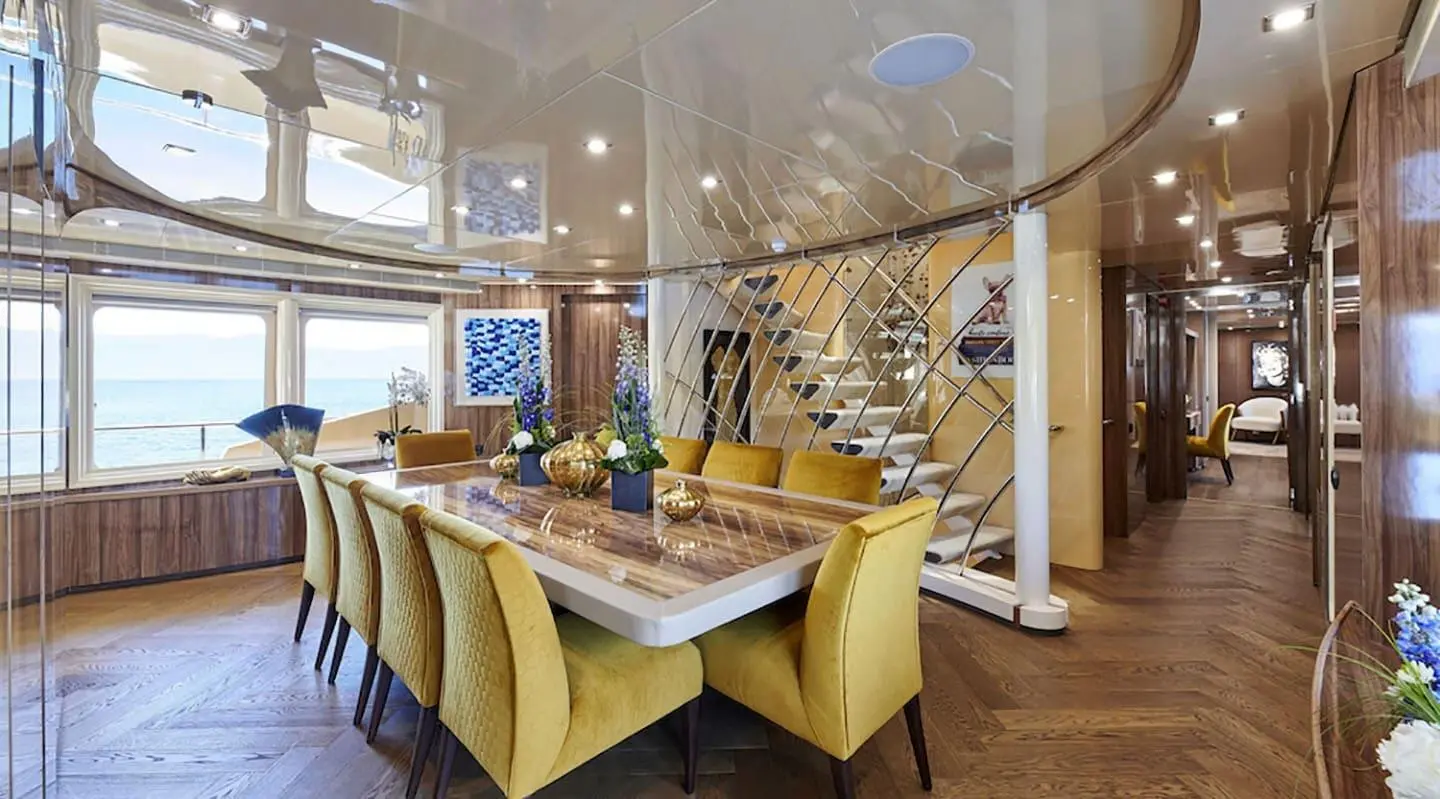 Daloli yacht dining area with long wood table and yellow chairs inside
