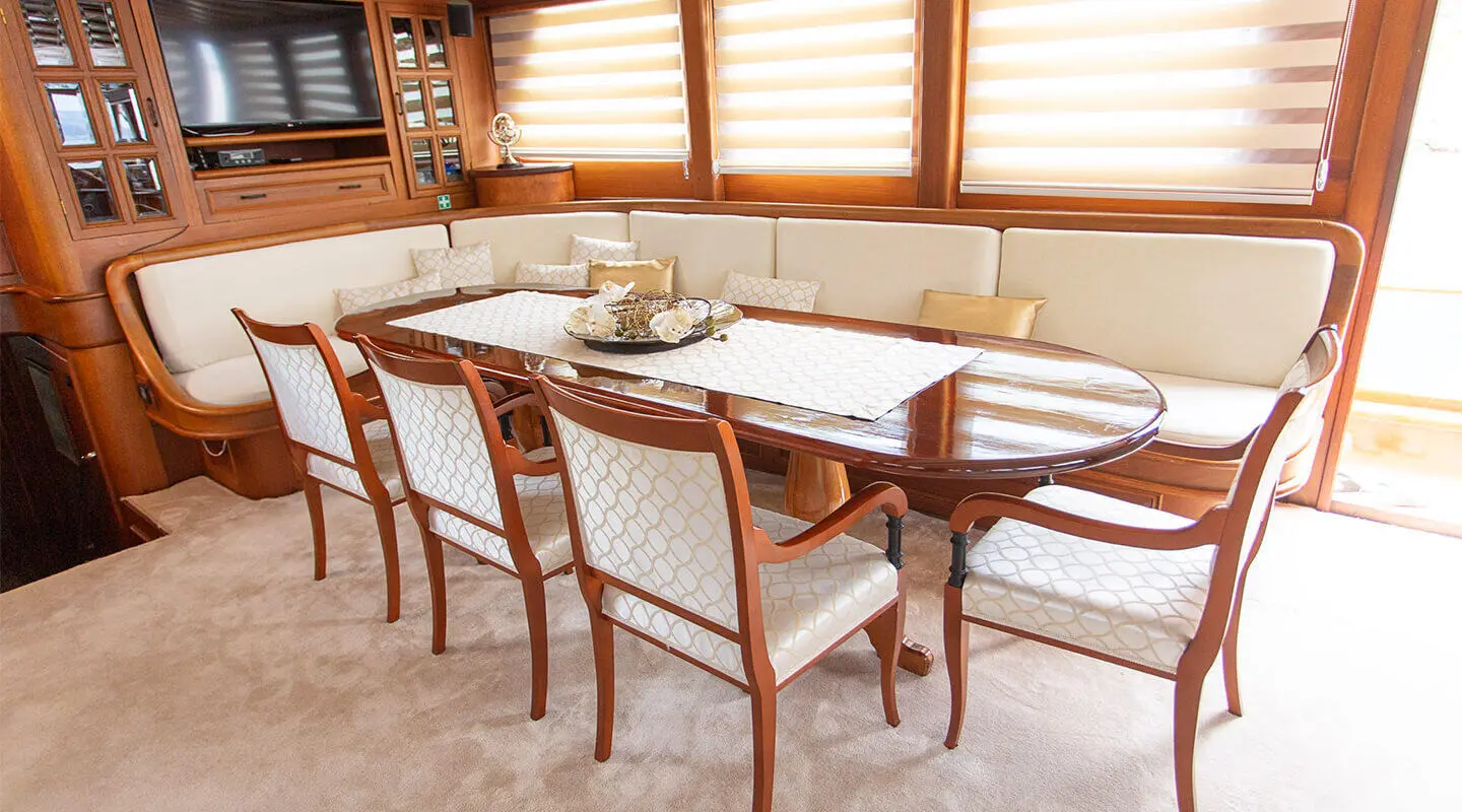 Dolce Vita luxury yacht dining table with wooden chairs on deck at sunset