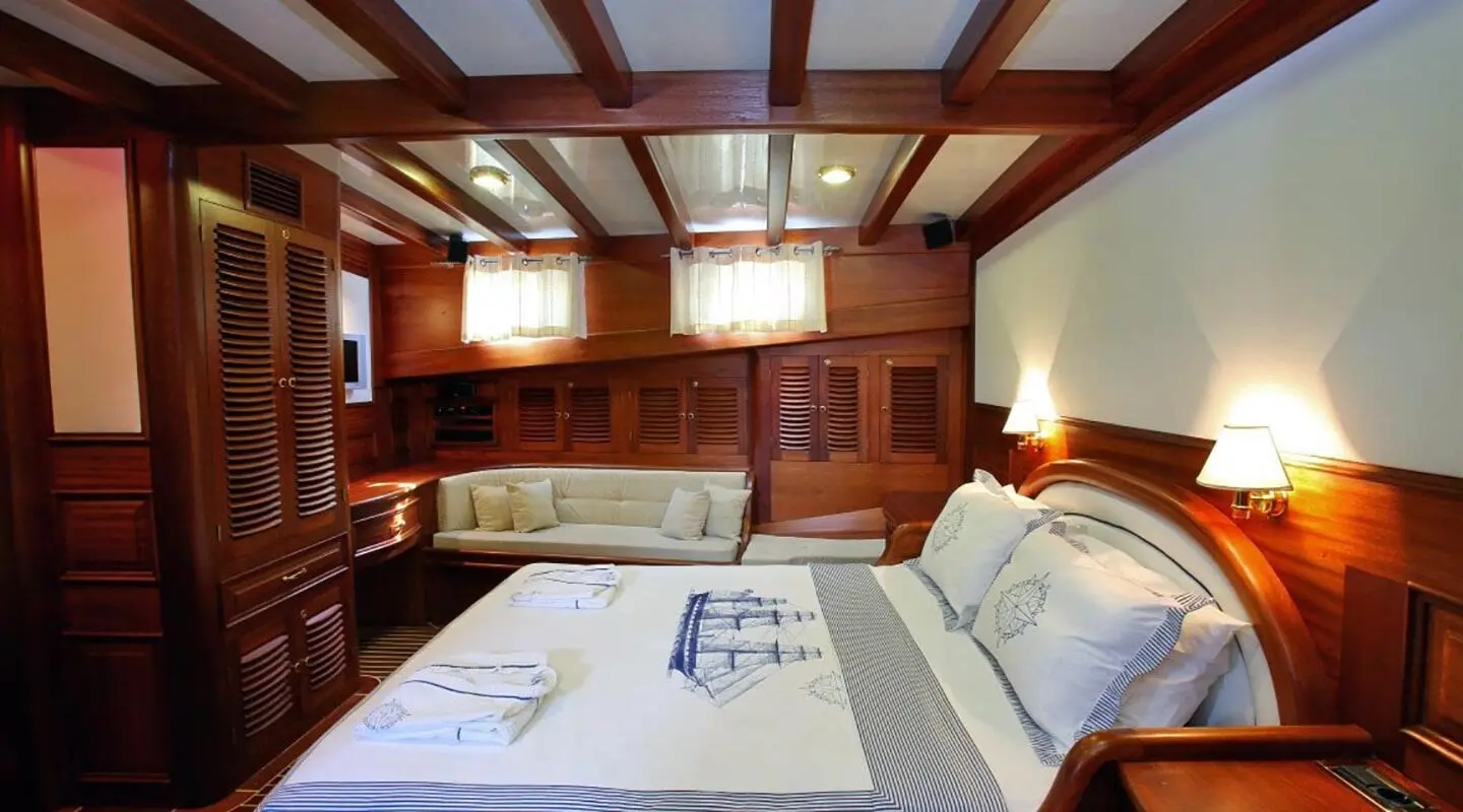 Kaya Guneri 4 gulet interior: wooden cabin with bed and seating area
