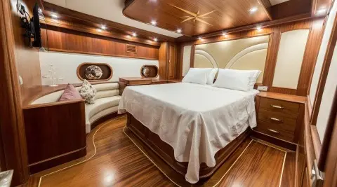 Halcon Del Mar yacht interior with two twin beds, warm wood panels, and porthole window