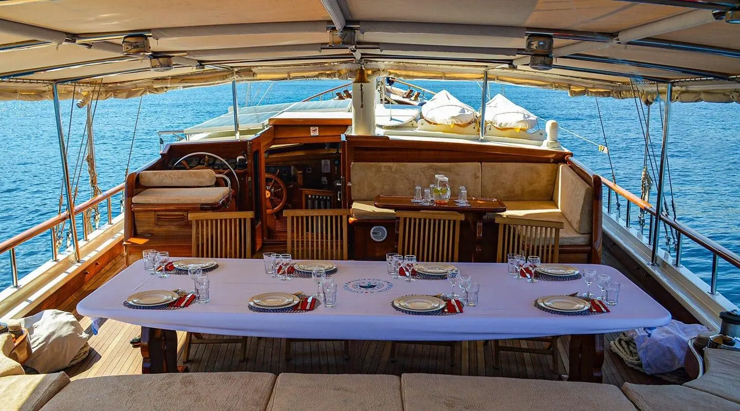 Enderim A yacht charter: dining table set under a shaded deck with ocean views