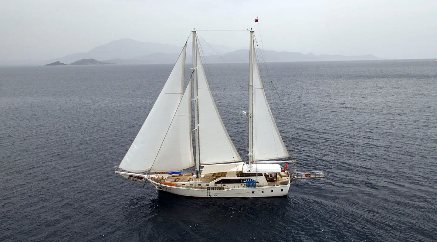 Kayhan 3 yacht sailing at sunset with white sails on calm sea