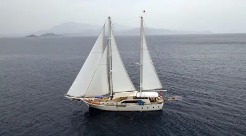 Kayhan 3 yacht sailing at sunset with white sails on calm sea