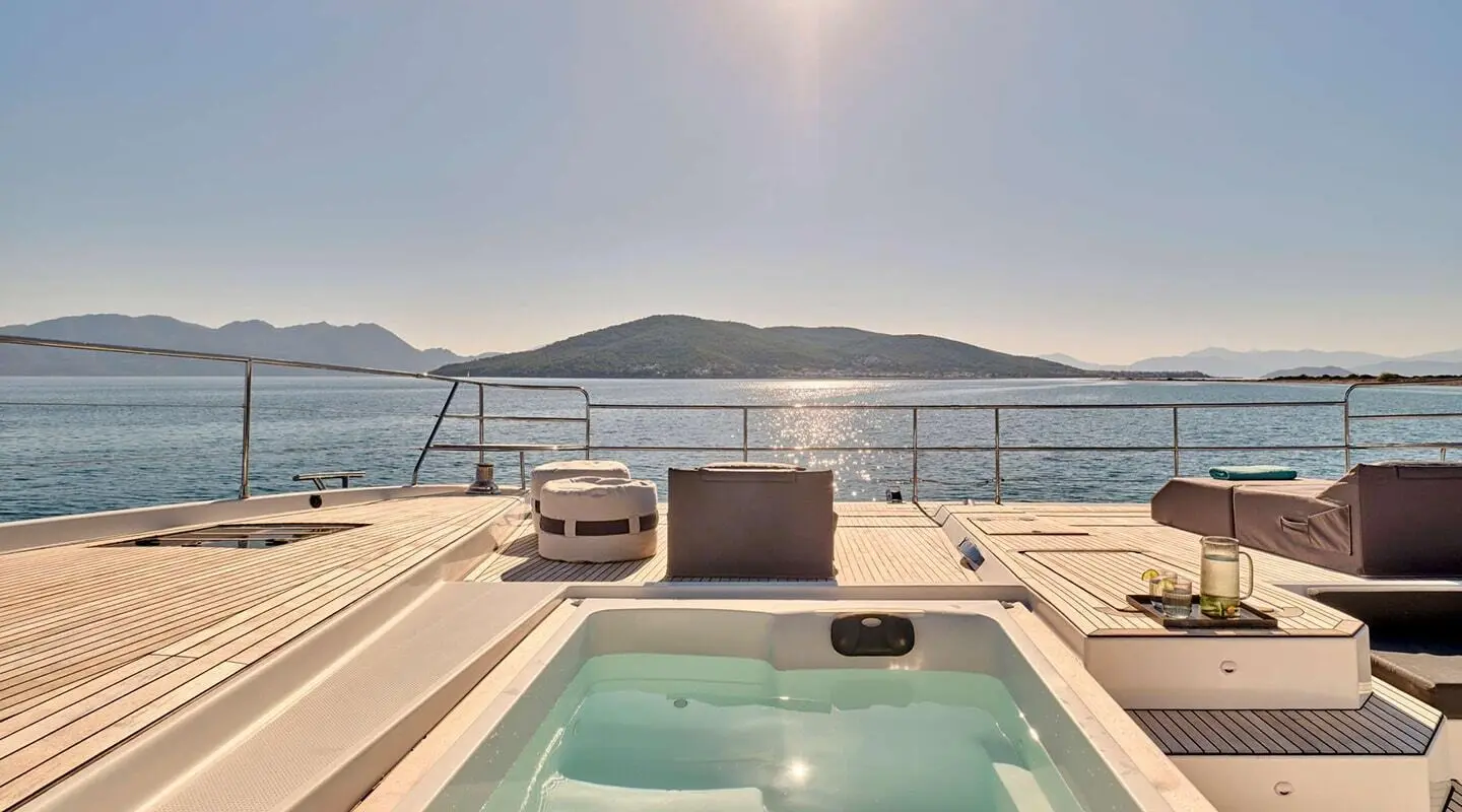 Christal Mio yacht deck with hot tub, sunlit water, and distant hills