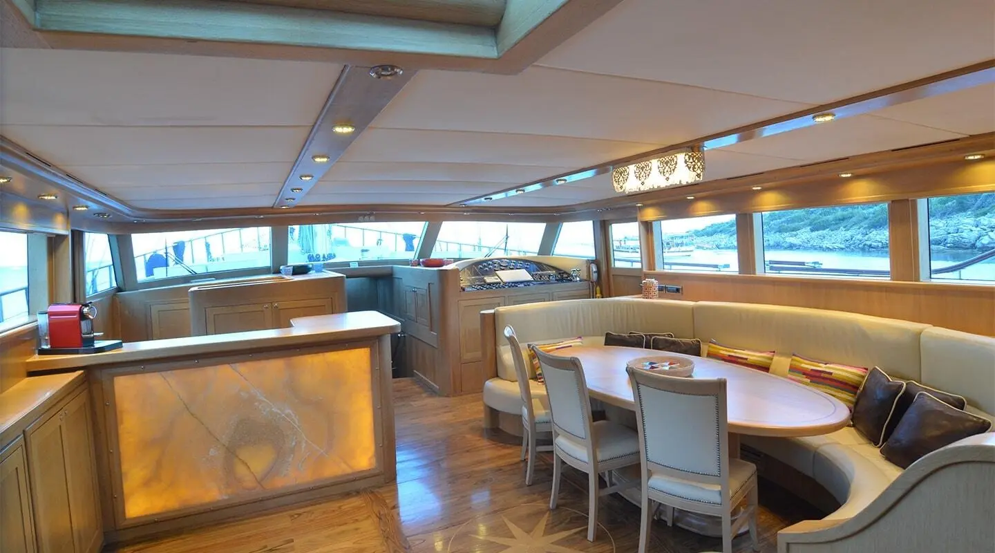 Blue Heaven yacht interior with dining area, large windows, and sunset light