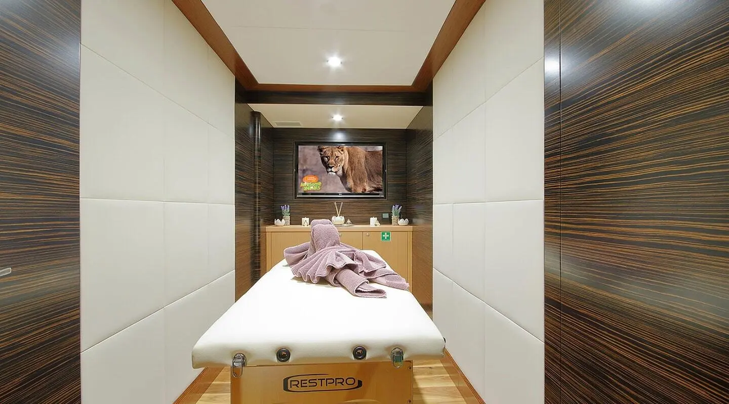 Meira yacht massage room with a bed, towels, and warm wood accents.