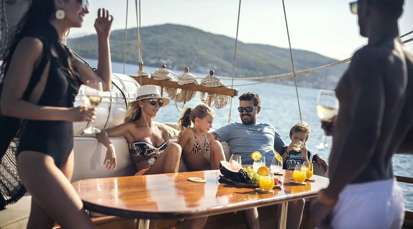 Entre Cielos yacht crew and guests at sunset on a wooden table onboard