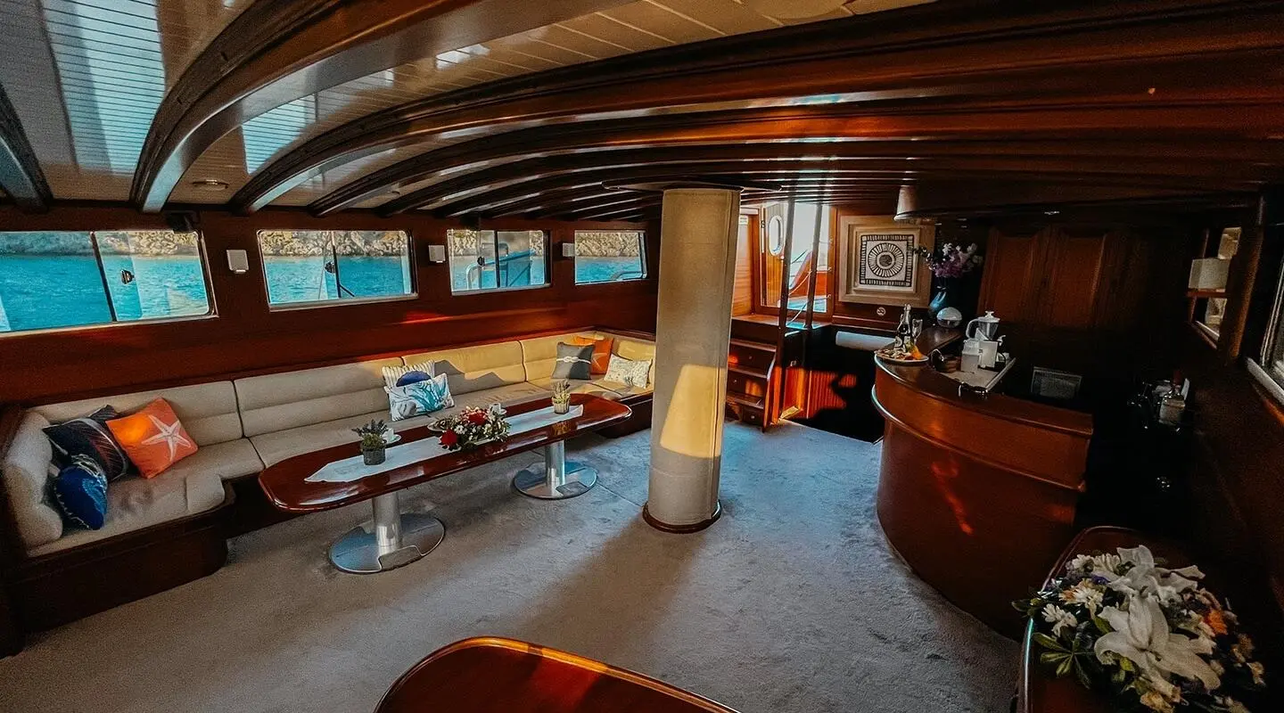 Indoor yacht lounge with wooden beams, seating, and warm lighting aboard Wicked Felina