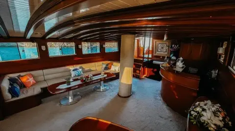 Indoor yacht lounge with wooden beams, seating, and warm lighting aboard Wicked Felina