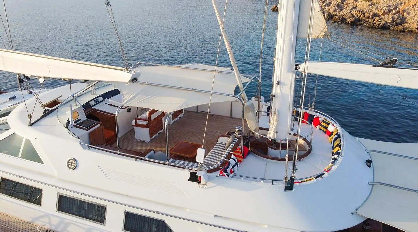 Top deck of Tamarita yacht with seating, steering area, and blue sea backdrop