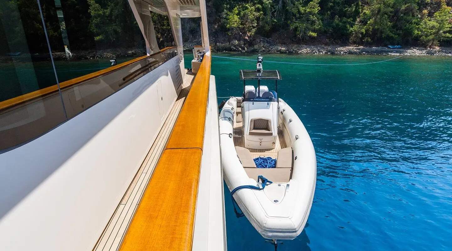 Takara One yacht alongside a teak deck and tender in clear blue water