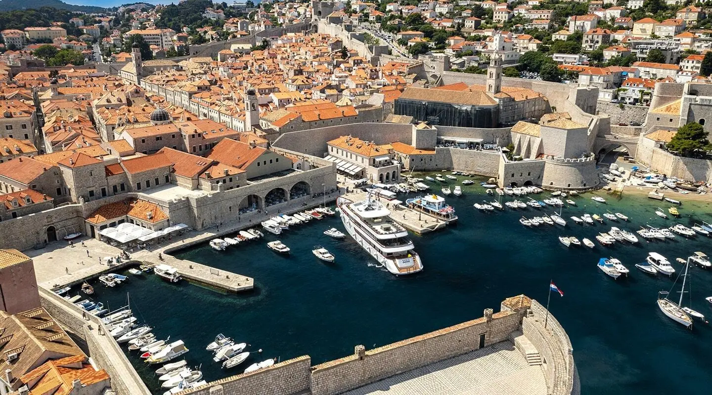 Yolo motor yacht docked in Dubrovnik harbor with historic stone walls nearby