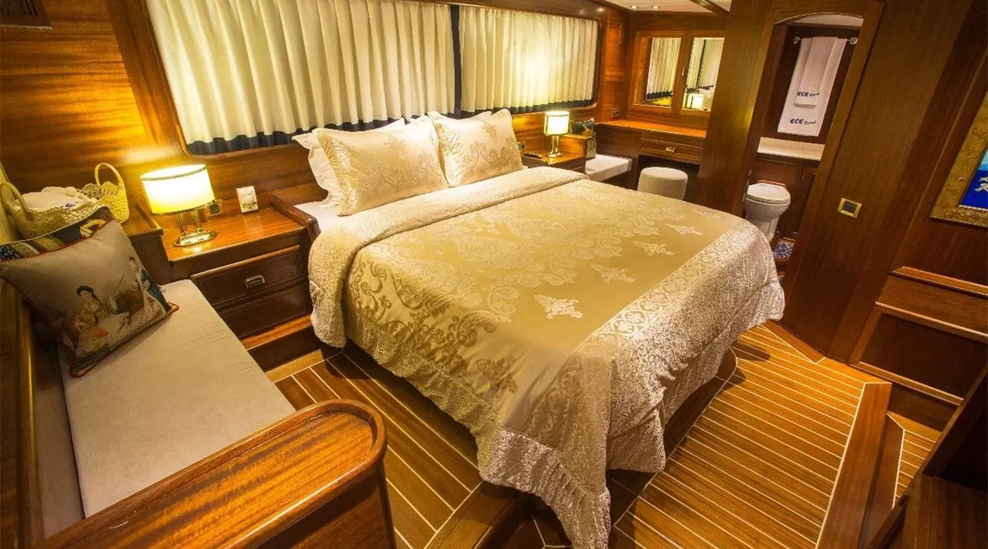 Elegant master bedroom aboard Ece Berrak yacht with cream bed linens and wooden cabinetry