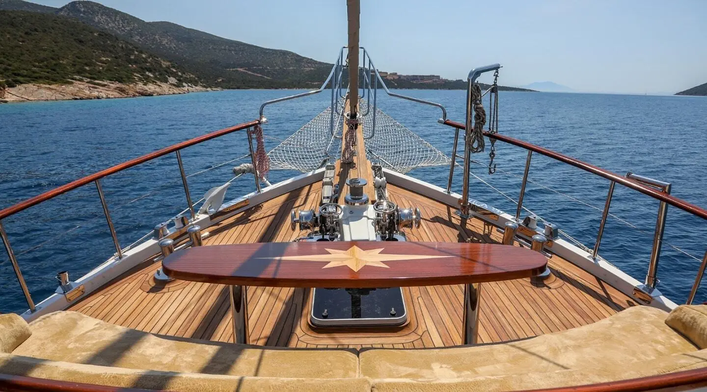View from the yacht Ulucinar bow deck showing wooden helm and rails at sunset