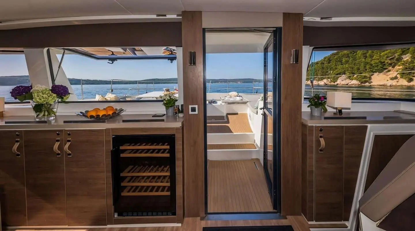 Aboard Ocean Lounge yacht: open sliding doors to deck, warm wood interior, ocean beyond