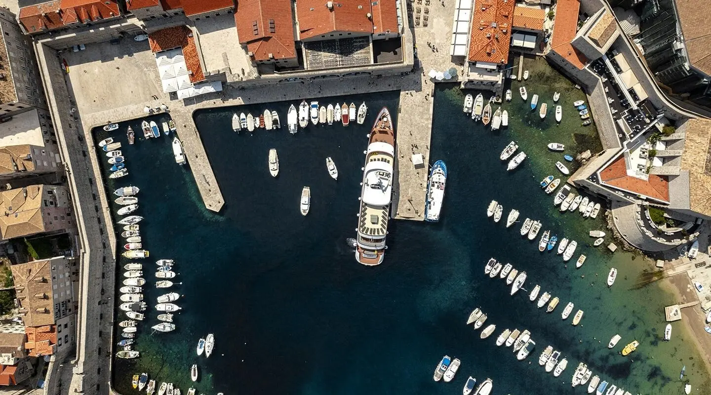 Aerial view of a yacht named Yolo docked in a marina with many small boats surrounding
