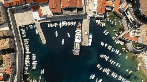 Aerial view of a yacht named Yolo docked in a marina with many small boats surrounding