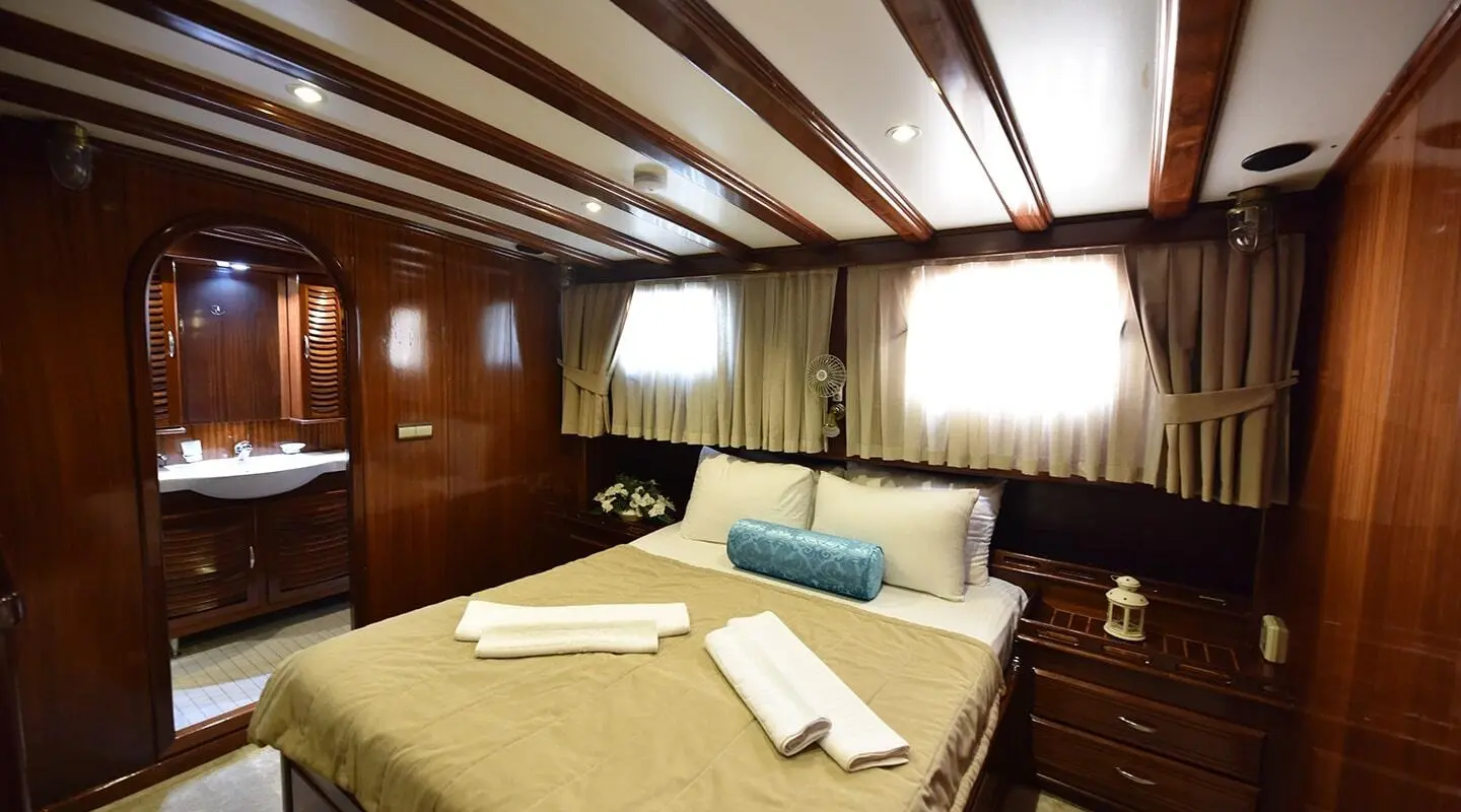 Interior cabin of Kayhan Kaptan yacht, wood paneling, bed, and seating