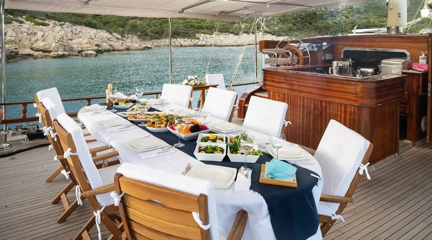 Estrella De Mar yacht charter with white seating, table, and sea view at sunset