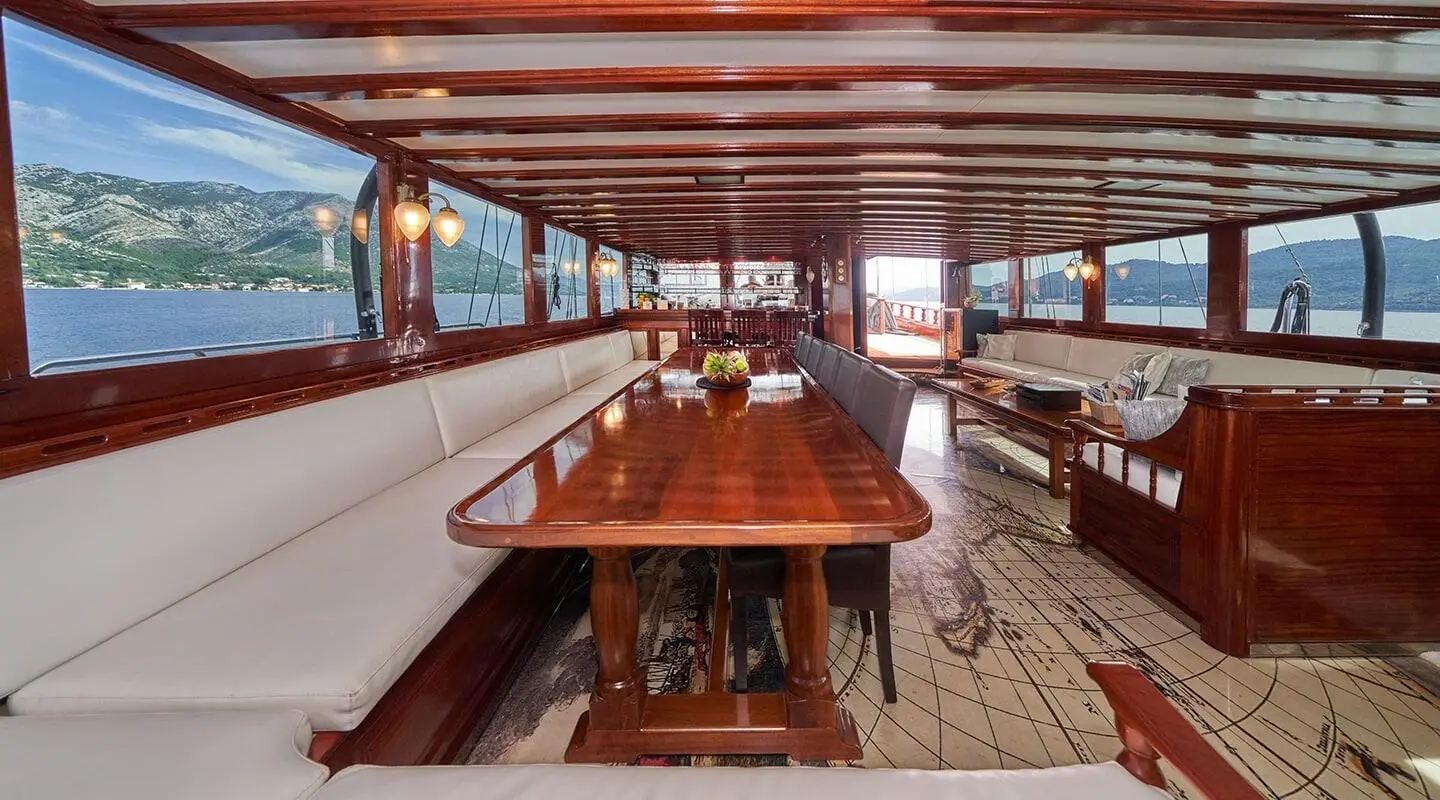 Stella Maris yacht interior with wooden dining table and cushioned seating