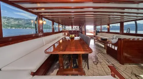 Stella Maris yacht interior with wooden dining table and cushioned seating