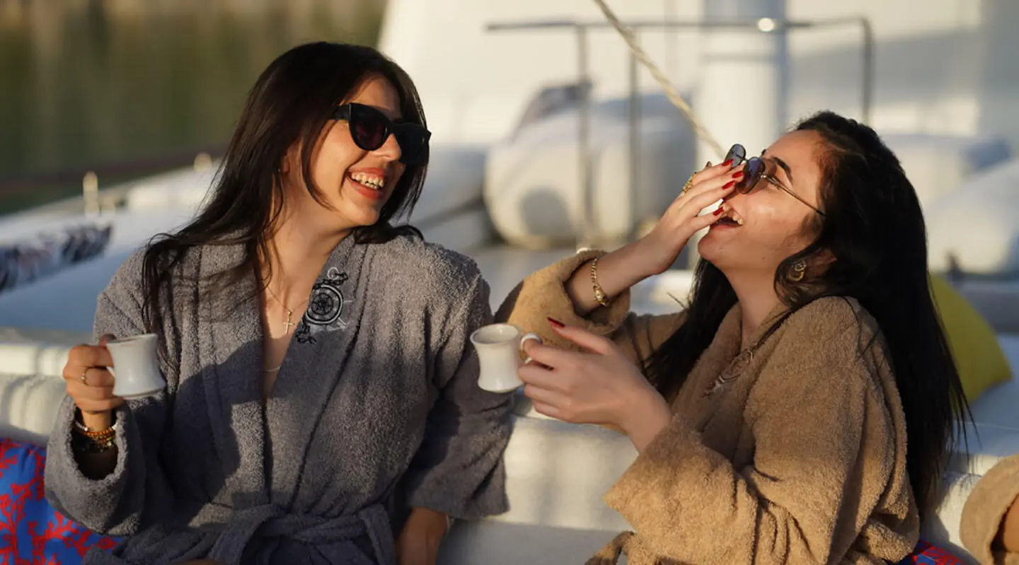 Two women on a gulet yacht, smiling and clinking glasses on deck