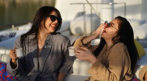 Two women on a gulet yacht, smiling and clinking glasses on deck