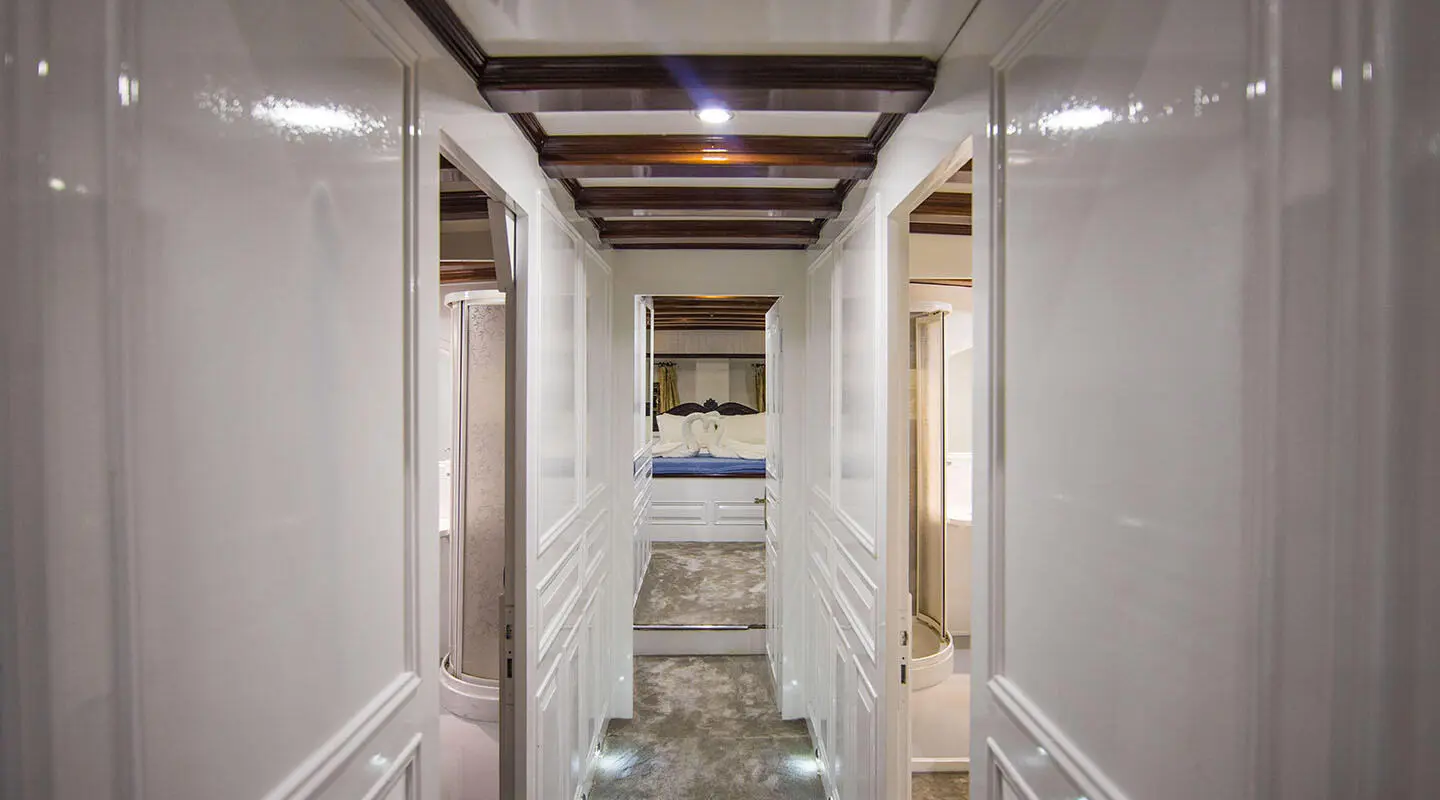 White corridor with doors on sides leading to a bedroom at the end