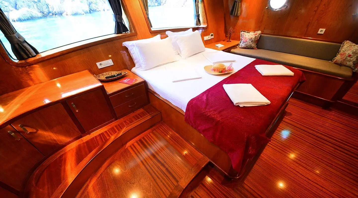 Luxurious Maya yacht interior with polished wood, red upholstery, and white bedding