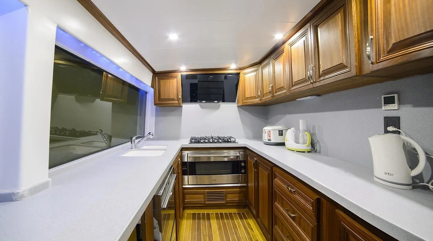 Bella Mare yacht interior: compact galley with wooden cabinets, stove, and sink