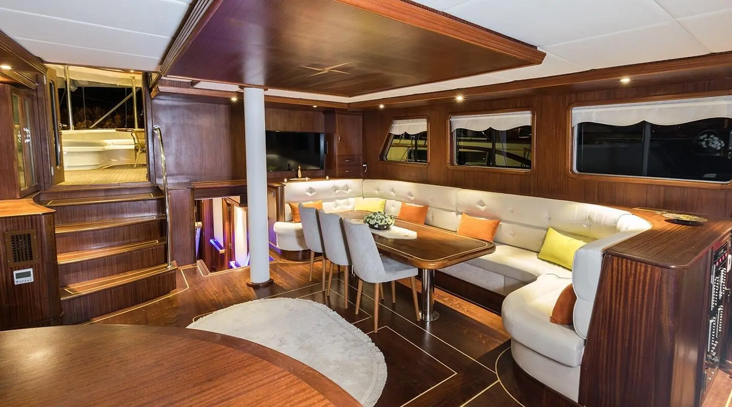 Inside view of Vista Mare yacht: wooden dining area with white and yellow cushioned seating