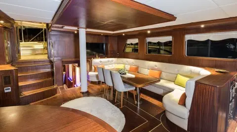 Inside view of Vista Mare yacht: wooden dining area with white and yellow cushioned seating
