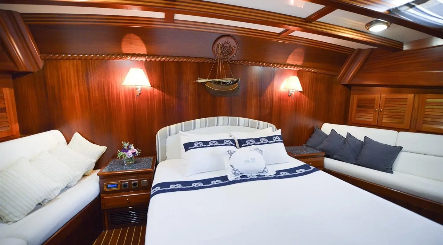 Ros Mare luxury gulet interior with bed and wooden cabin, warm lighting