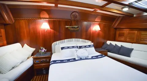 Ros Mare luxury gulet interior with bed and wooden cabin, warm lighting