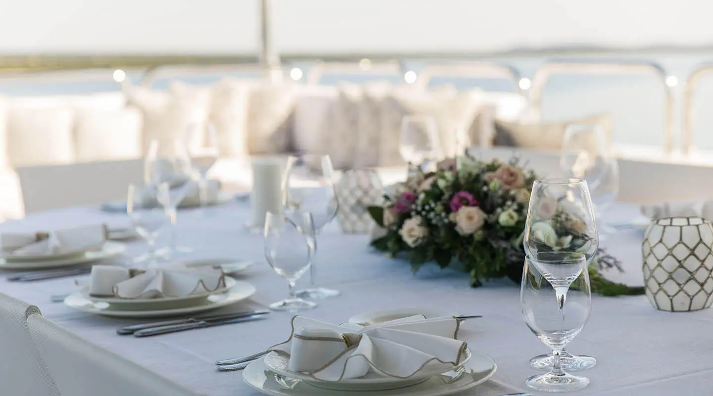 Alalya yacht dining table set for luxury charter with flowers and glassware on deck