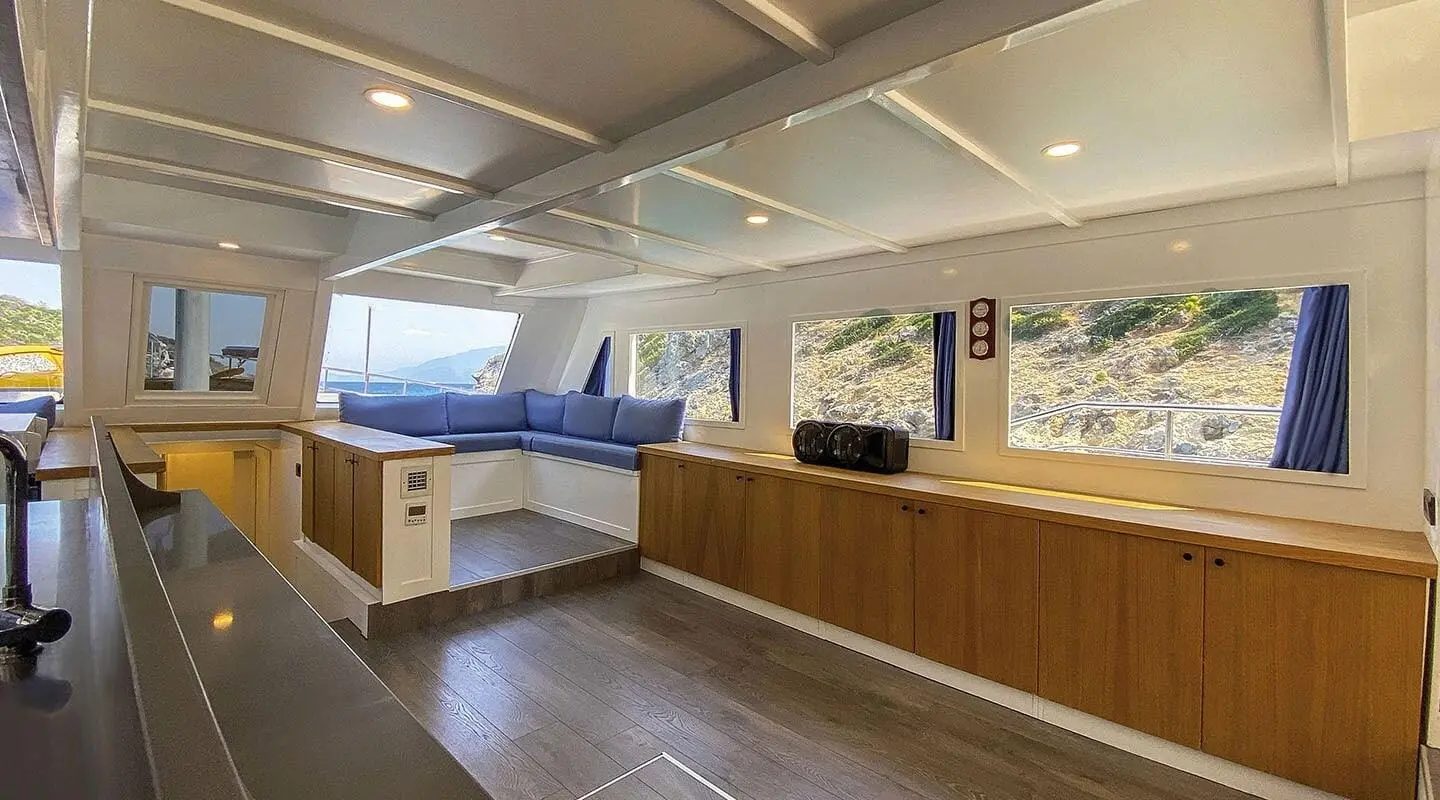 Maske 5 interior: spacious saloon with L-shaped blue cushions and wood cabinetry