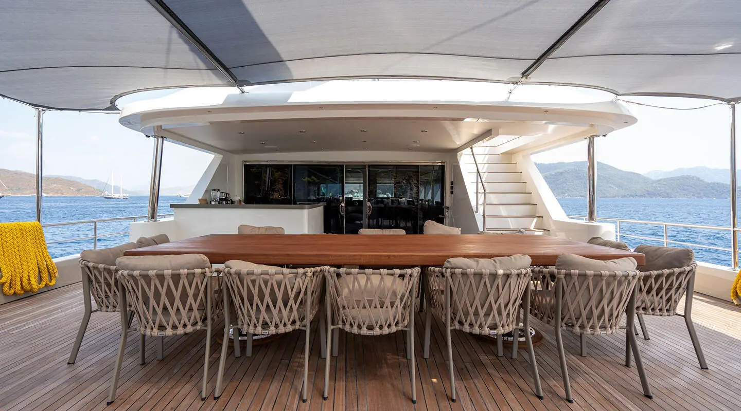 Outdoor dining area on De Love yacht with wooden bar and wicker chairs
