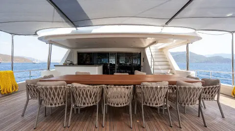 Outdoor dining area on De Love yacht with wooden bar and wicker chairs